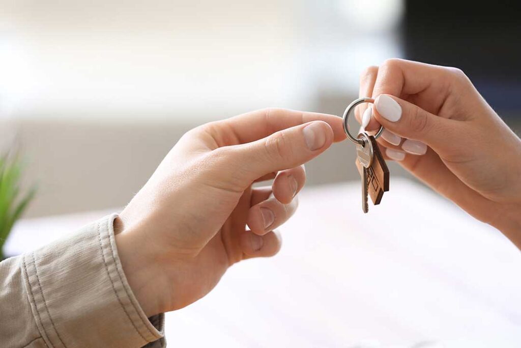 A couple reviews home search documents together at a kitchen table, surrounded by moving boxes and paperwork.
