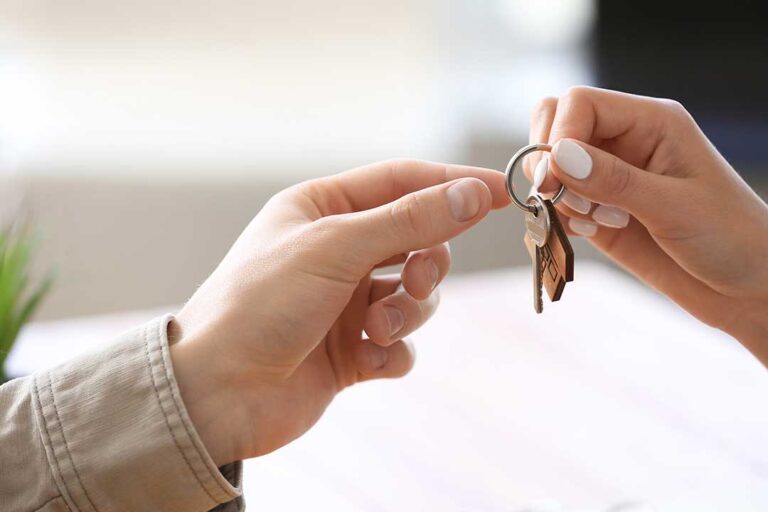 A couple reviews home search documents together at a kitchen table, surrounded by moving boxes and paperwork.