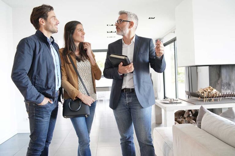 A couple reviews home purchase documents and closing cost statements around a kitchen table.