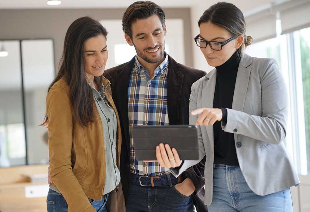 A couple reviews a home inspection report and purchase documents at a kitchen table.