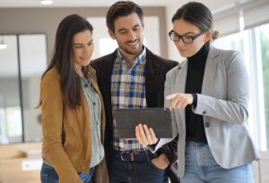 A couple reviews a home inspection report and purchase documents at a kitchen table.